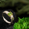 Elegant silver birthstone ring with peridot, set against dark natural backdrop