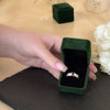 Hand presenting amethyst birthstone ring in elegant pink jewelry box
