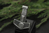 Front view of a Viking Thor's Hammer pendant with knot design, displayed on a black jewelry stand with greenery background.