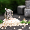 Snake-inspired ring with polished and scale-textured bands, handcrafted silver jewelry on mossy stones