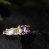 Amethyst silver ring with gold bezel and side zirconia in forest-inspired background