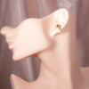 Gold floral stud earrings with pearl drop, worn on model for elegant styling