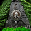 Luxury handcrafted Spartan shield pendant resting on dark stone with greenery – natural styled jewelry photo.