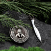 Flat lay of exclusive Spartan pendant and sword made of sterling silver, styled with green pine branches and natural textures.