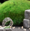 Handcrafted silver filigree ring displayed on moss with nature-inspired background