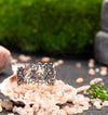 Artisan silver filigree ring with vintage vibes, surrounded by petals and stones