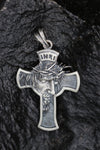 Sterling silver INRI cross necklace placed on dark stone with close-up on Jesus Christ’s face and crown of thorns