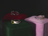 Luxury packaging: amethyst and peridot rings displayed in green and red velvet boxes